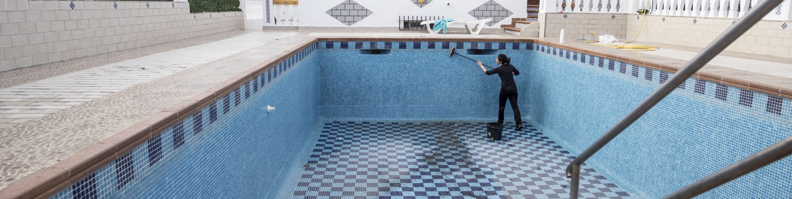 Woman-cleaning-drained-pool-2048w
